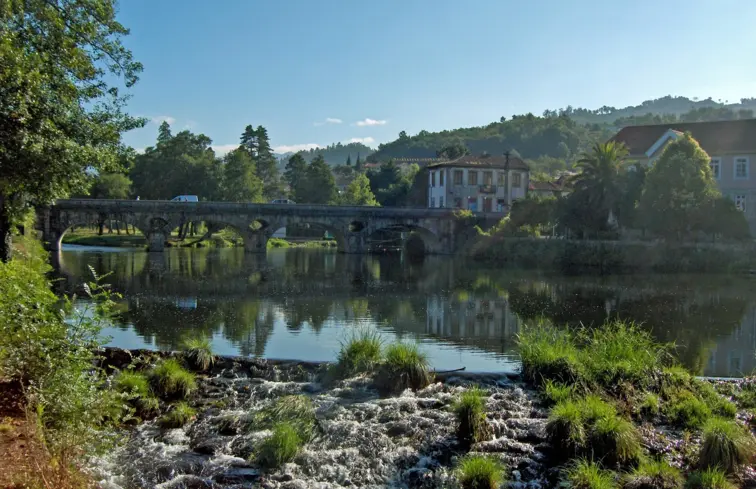 Ponte Velha de Arcos de Valdevez, onde passa o rio Vez, num dia assolarado, no lado direito há árvores verdes.
