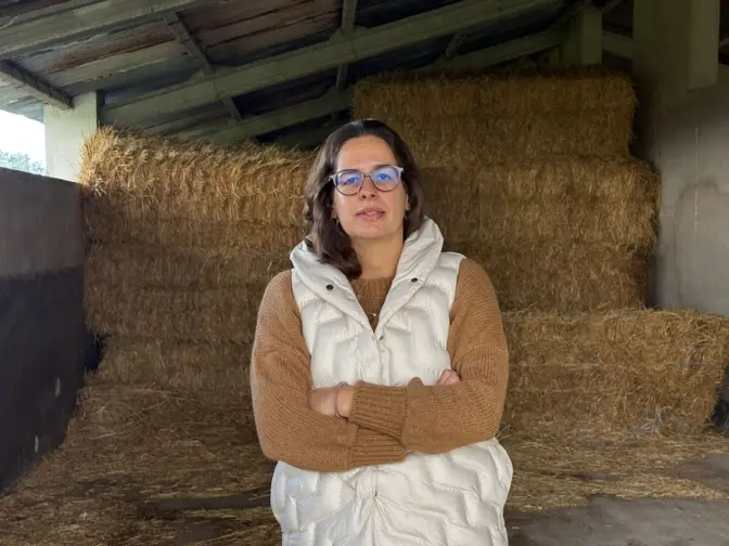 Fotografia de frente de Joana Vacas Freixa na sua exploração com fardos de palha atrás de si