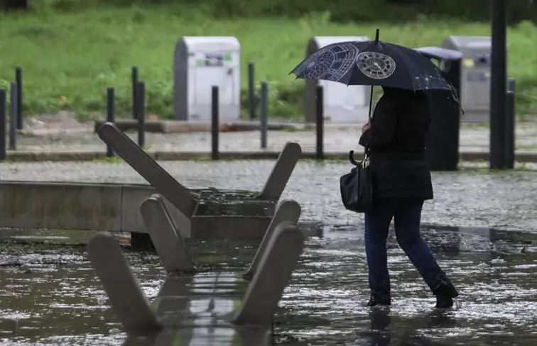 Mulher a caminhar com um guarda-chuva aberto