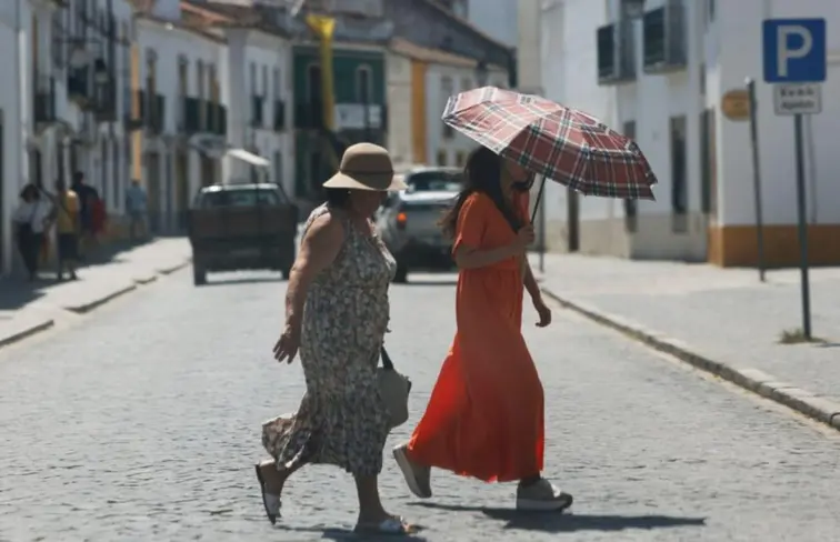 Duas mulheres a caminhar debaixo de sol